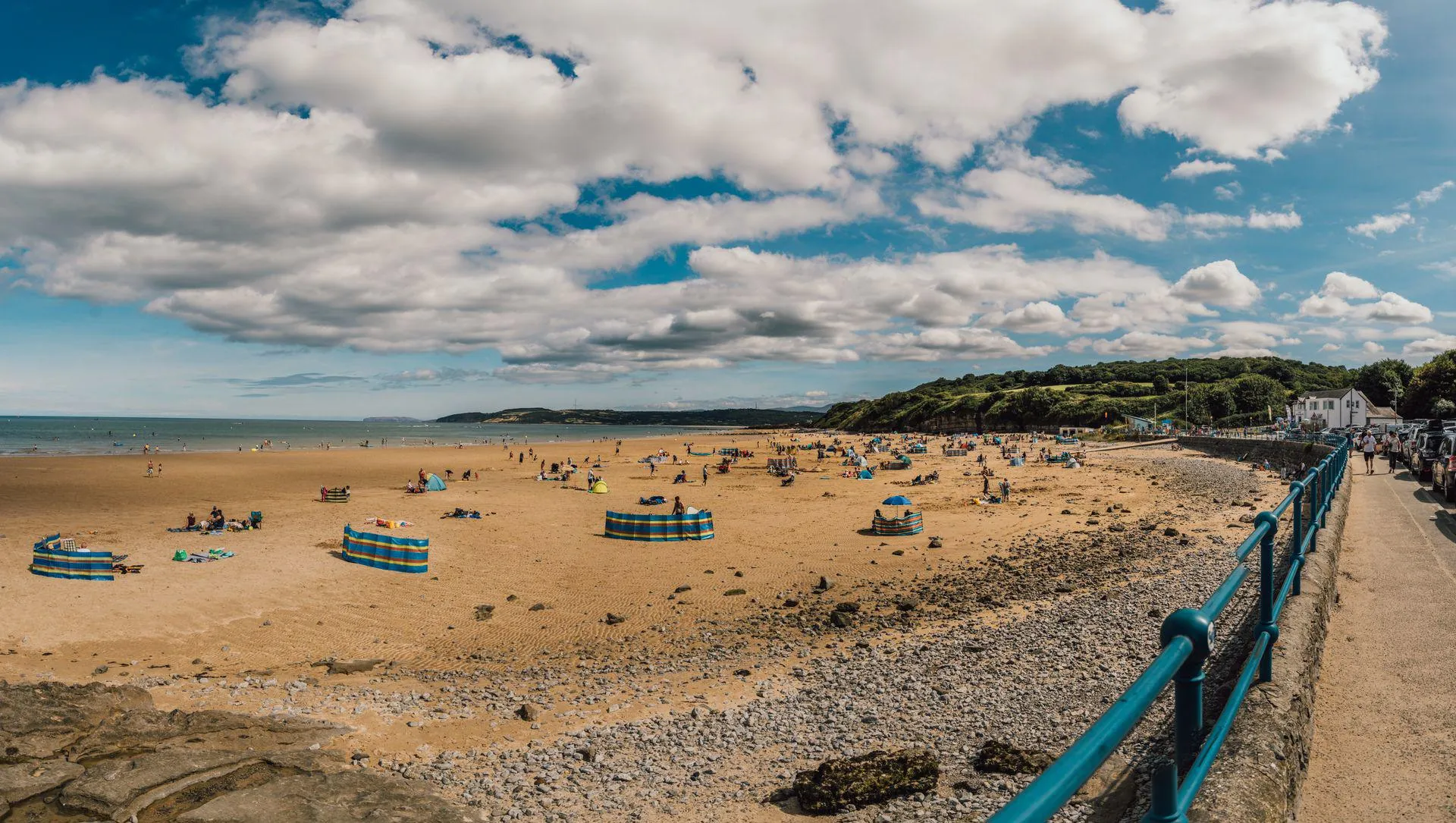 Benllech beach with wind cheaters and blue sky with white clouds