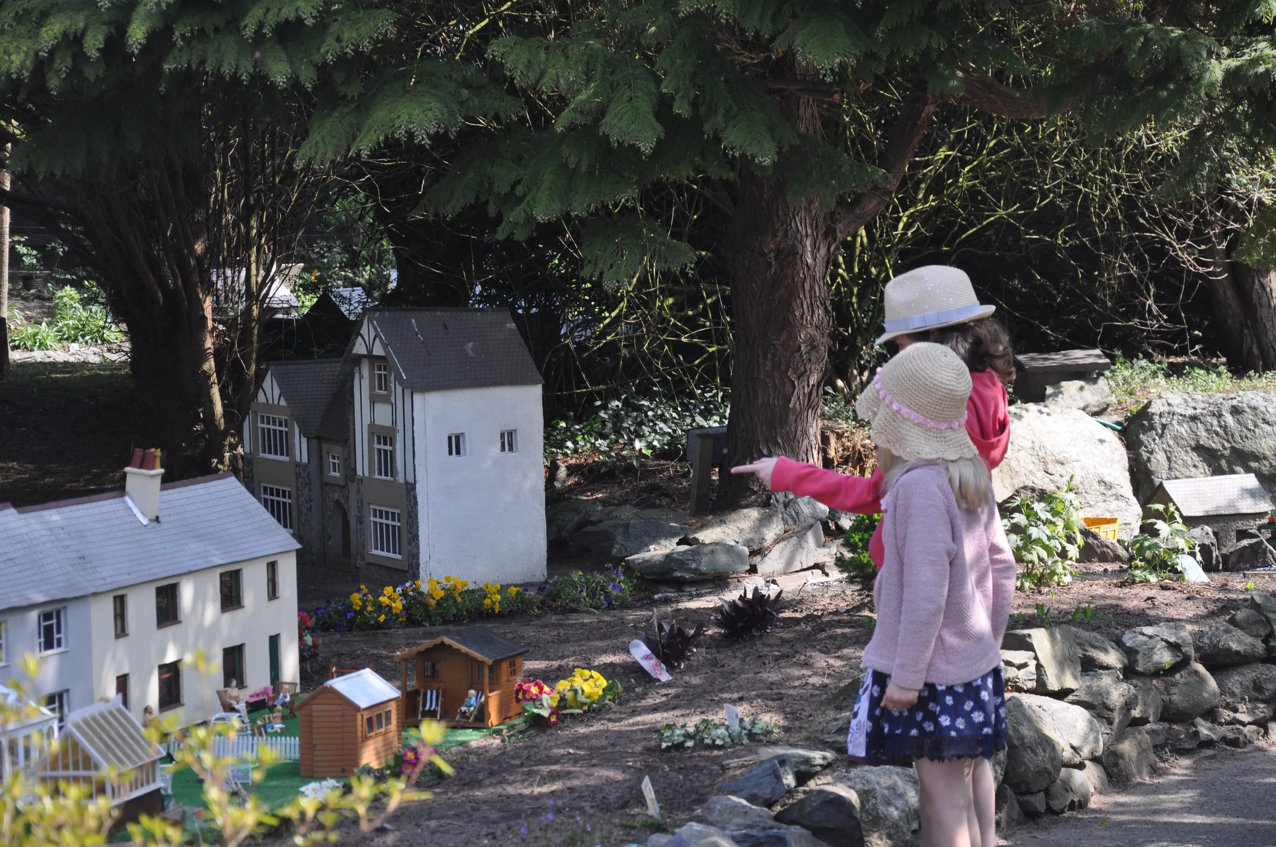 Dwy ferch fach yn pwyntio at y model yn yr heulwen