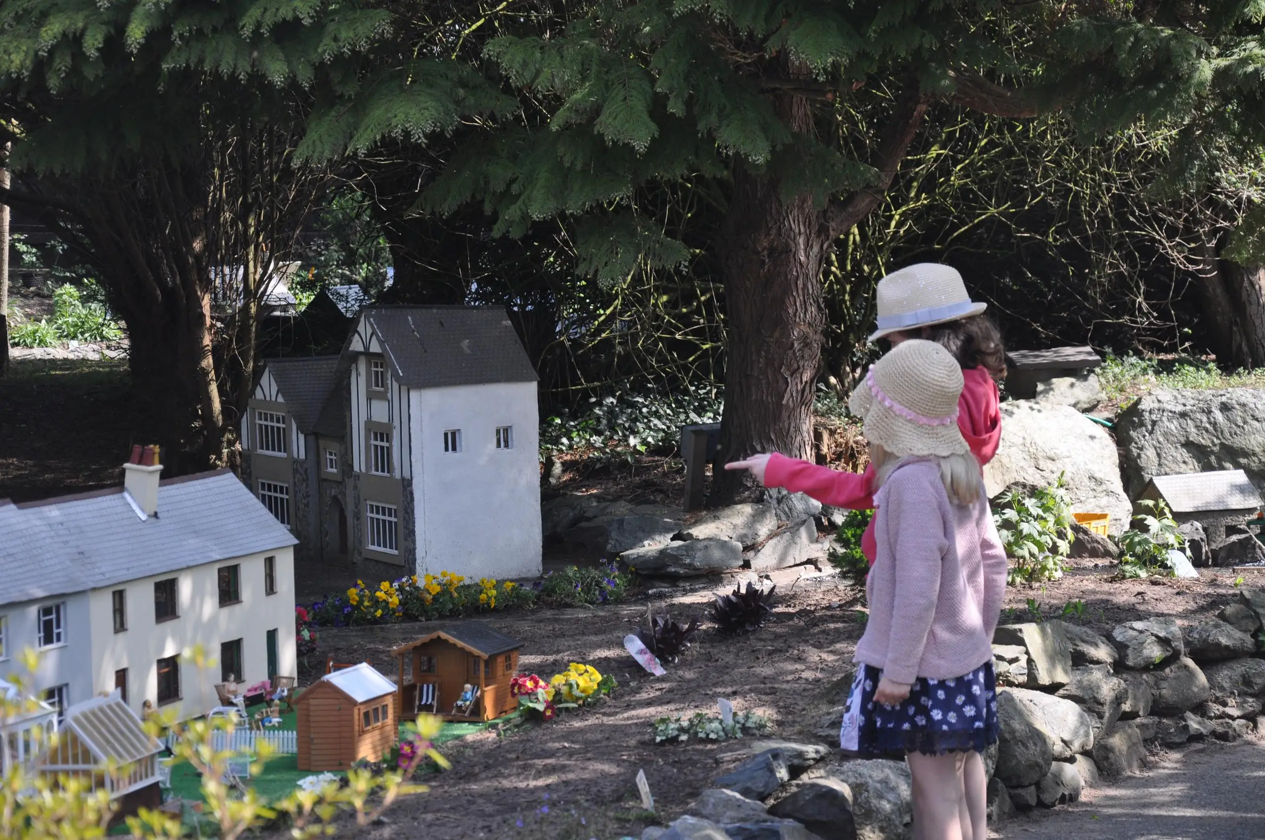 Dwy ferch fach yn pwyntio at y model yn yr heulwen