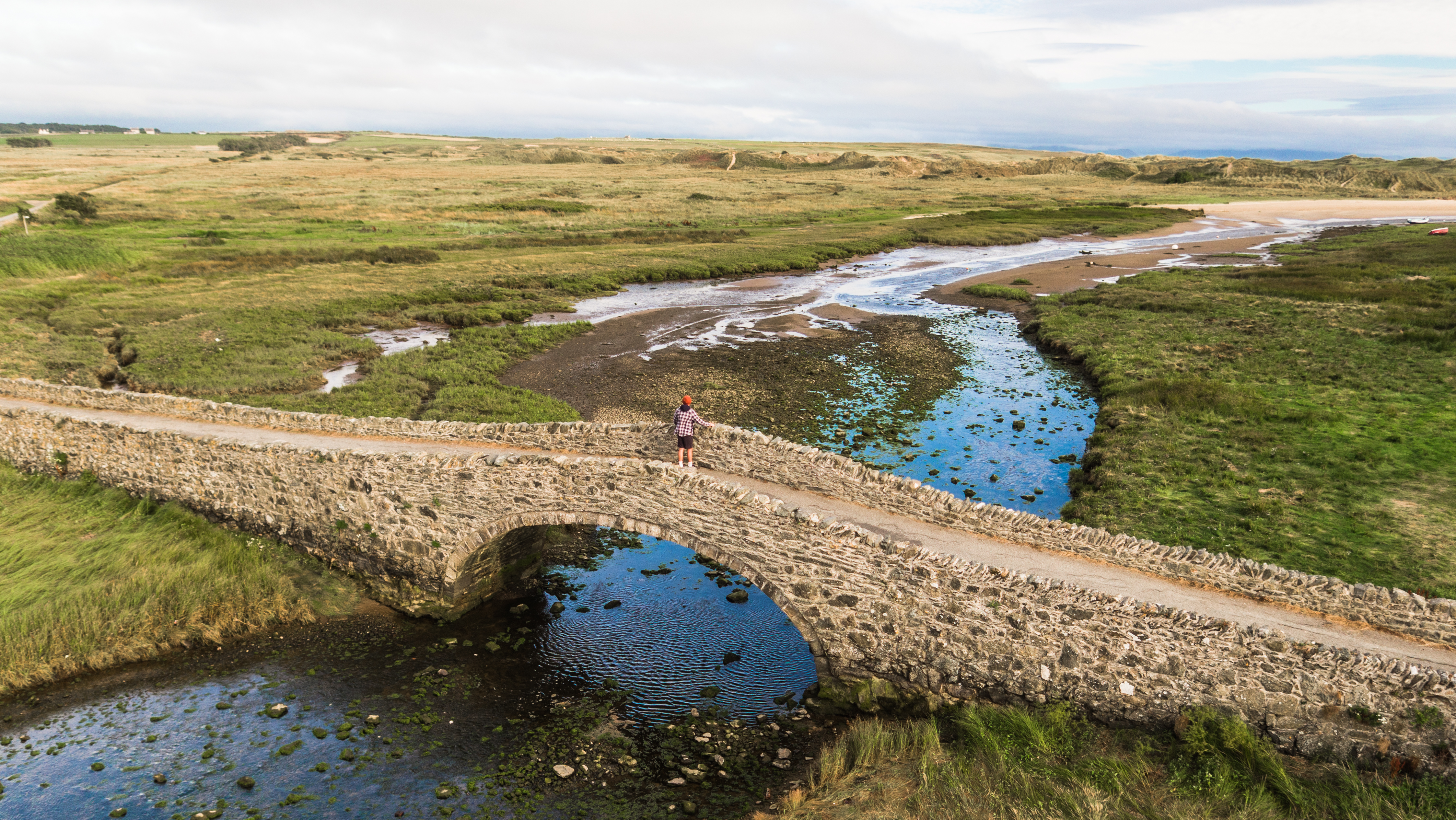  Pont Aberffraw yn edrych allan tuag at y twyni tywod gyda llanw isel gyda chymylau cirrostratus yn ffurfio ar y dde