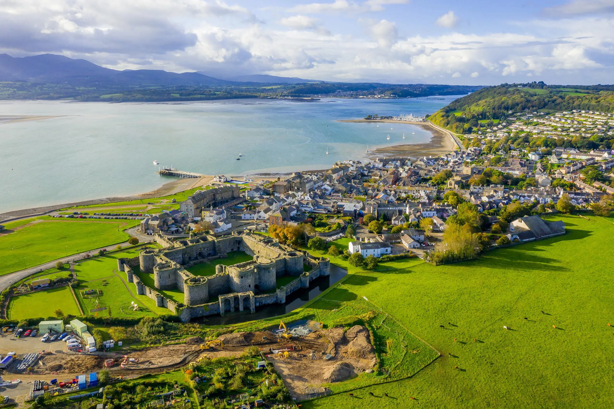 Golygfa o'r awyr yn edrych i lawr ar Gastell Biwmares a'r stryd fawr gyda'r Fenai y tu ôl