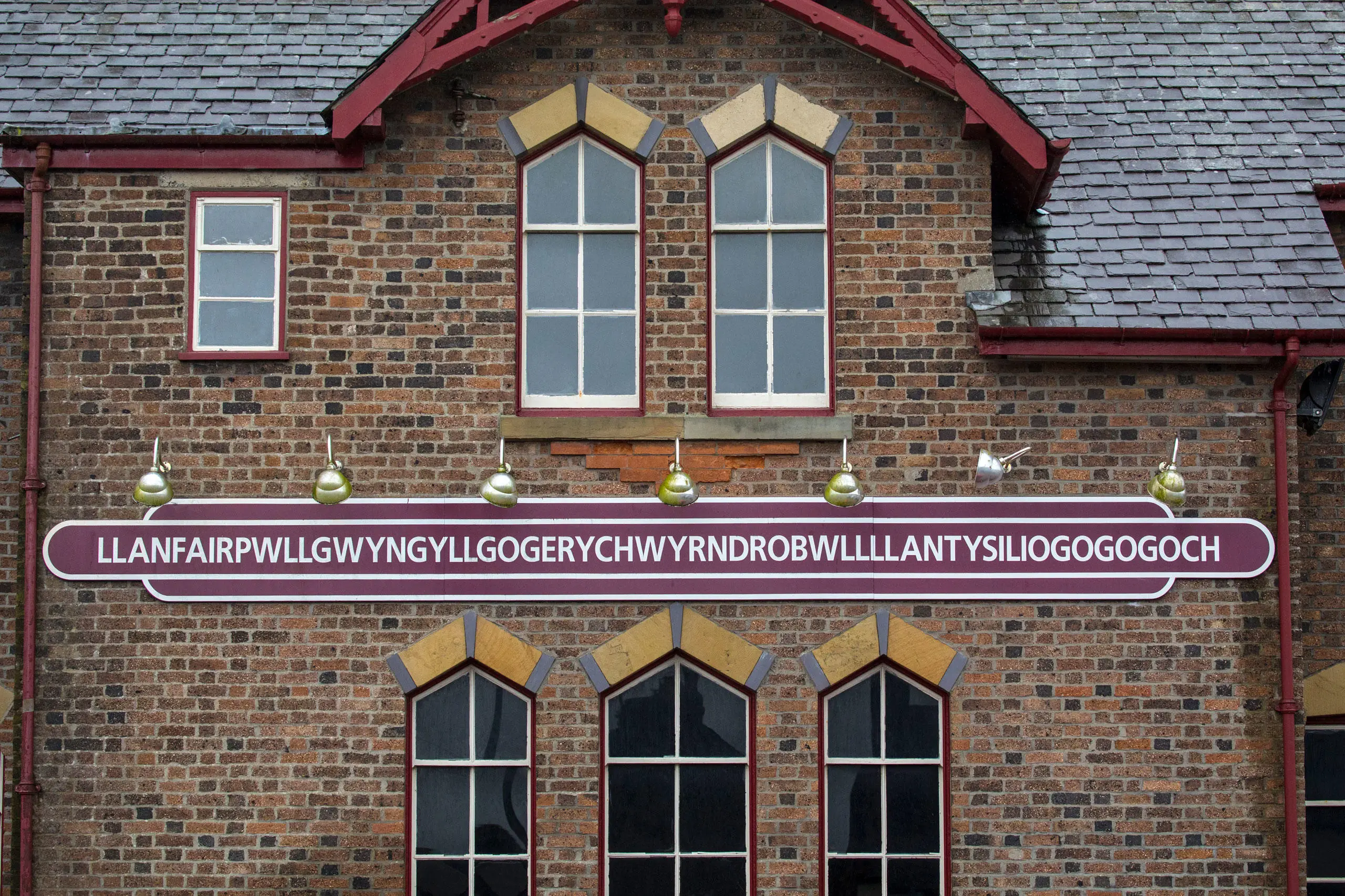 Arwydd hir o enw'r pentref ar adeilad yr orsaf