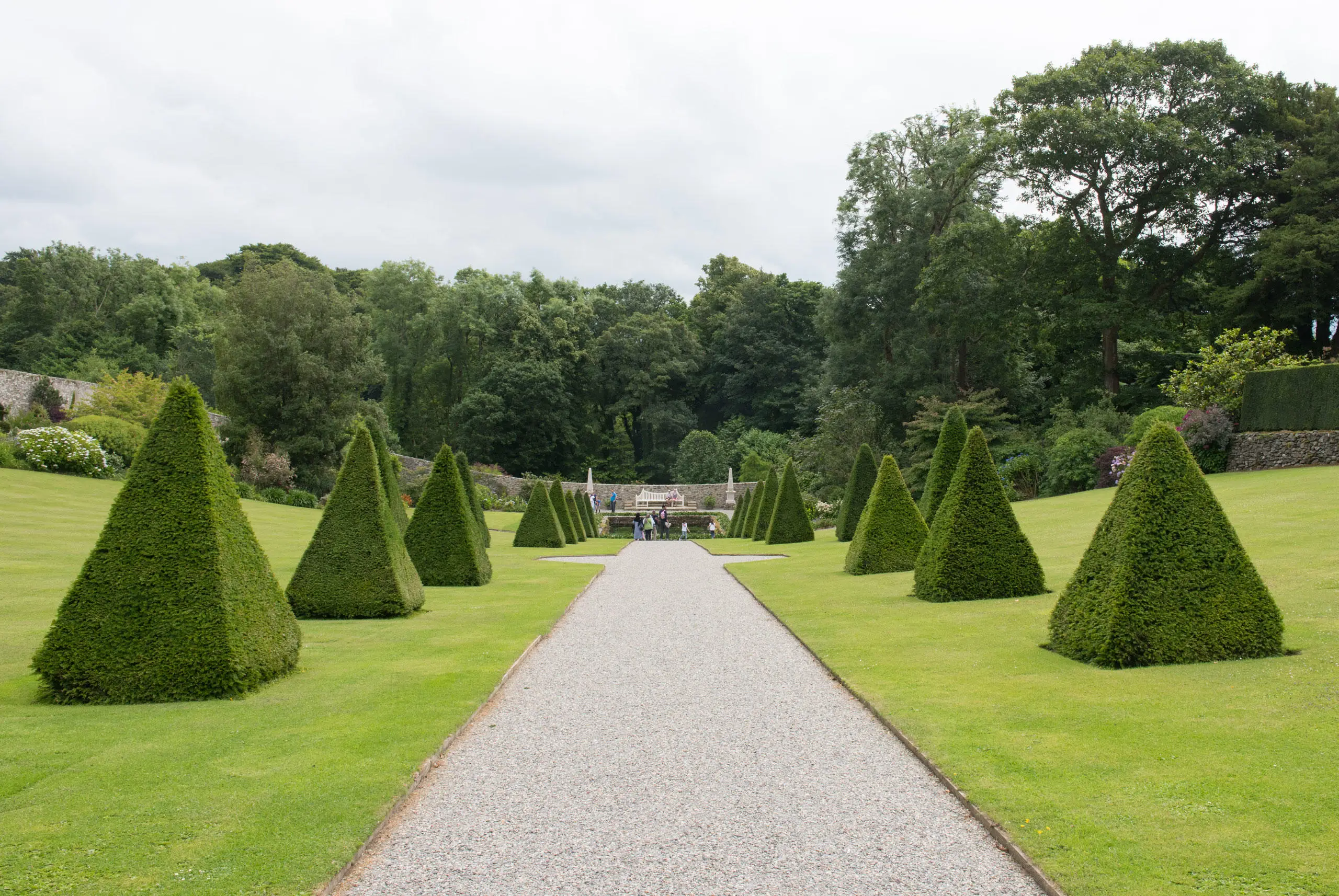 Tocwaith siâp pyramid y ddwy ochr i lwybr graean yng ngerddi Plas Cadnant